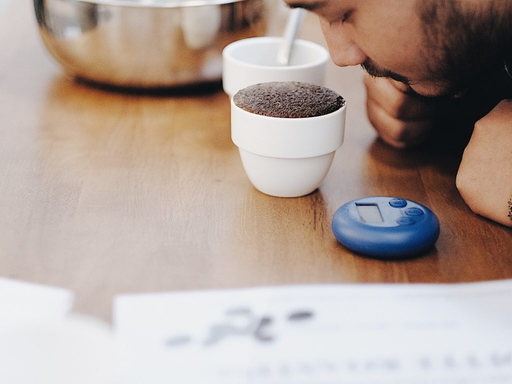 penyeduh sedang menghirup aroma kopi dari cupping bowls